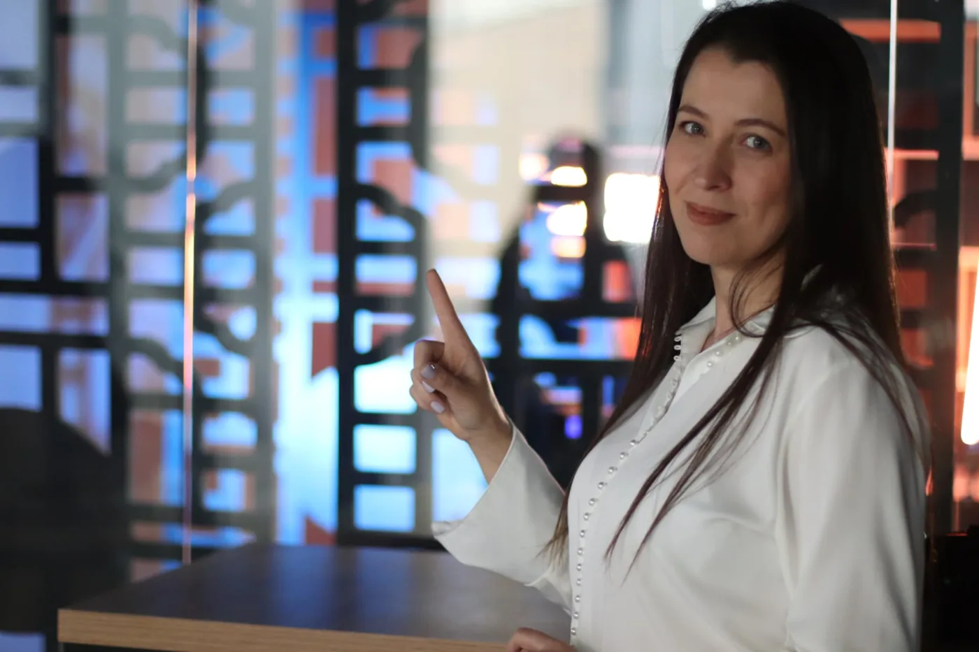 Profissional em blazer branco apontando durante uma apresentação